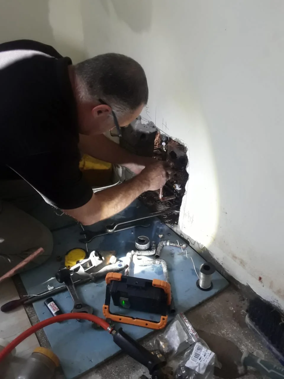 Bobby working on pipework inside an opened wall