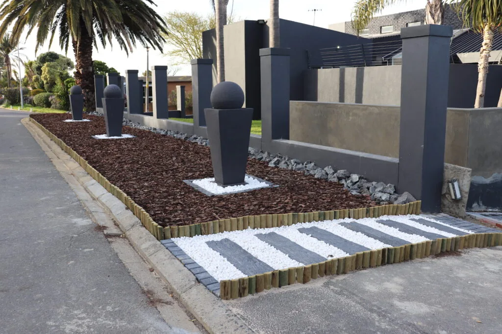 Landscaped planting bed with bark, stone and timber edging, from Top Trimmers