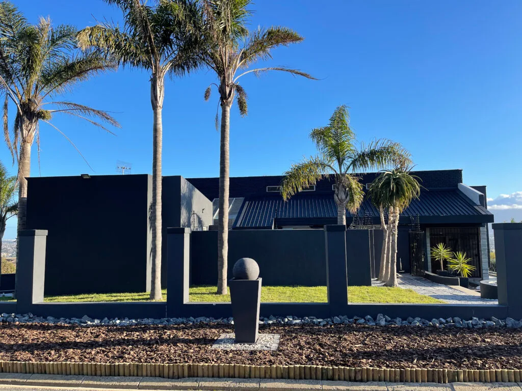 Completed outdoor landscaping with palms and stone-edged beds from the Top Trimmers gallery
